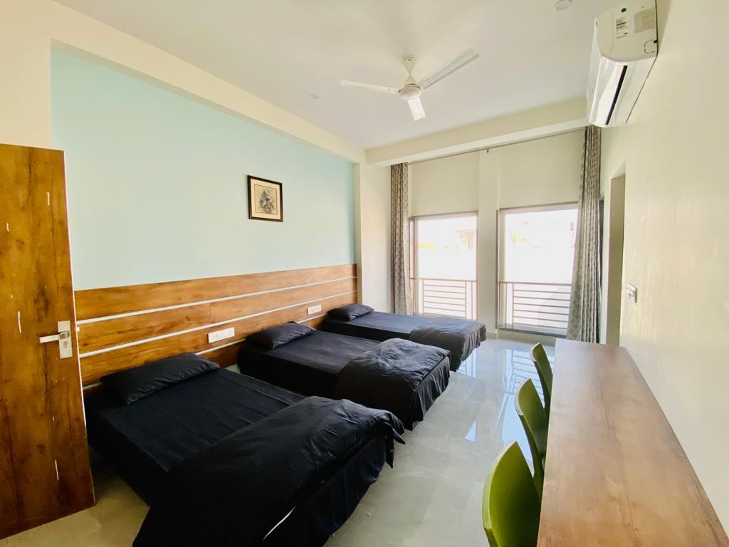 Triple sharing AC room with individual study tables at Anand Luxury Girls Home, Jagatpura